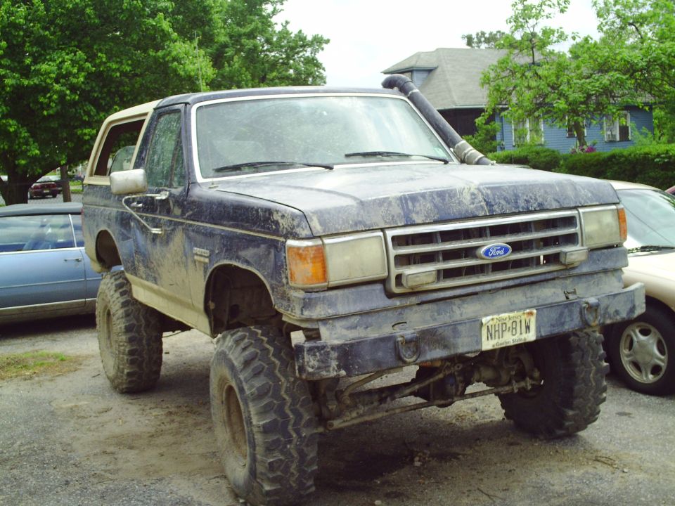 1990 Ford Bronco lifted with snorkel, parked next to another car