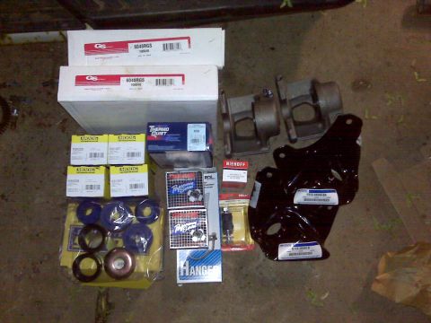 1995 Ford Bronco - Various vehicle parts are laid out on the floor, including suspension components and metal brackets.