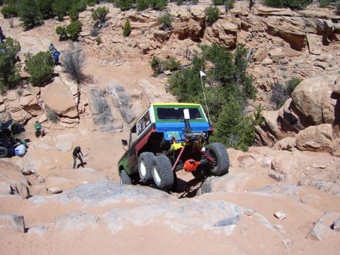 1991 Ford Bronco - Off-road vehicle navigating a challenging rocky trail with spectators present.