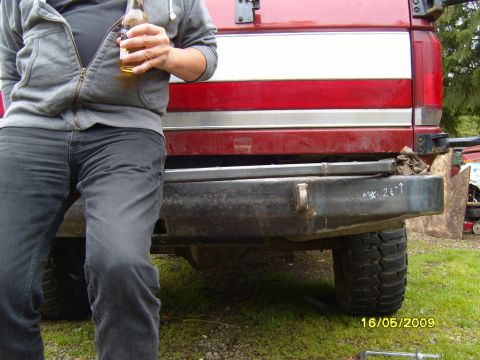 1989 Ford Bronco - Custom rear bumper with chalk markings is visible on a red vehicle. The tailgate above features red and white stripes.