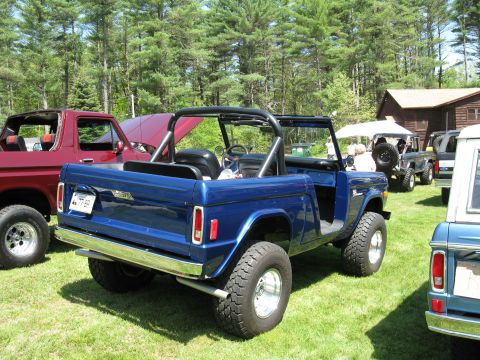 1973 Ford Bronco - A blue Ford Bronco is parked on a grassy field next to other vehicles.
