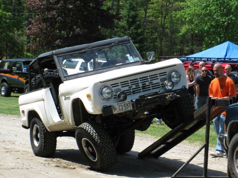 1973 Ford Bronco - A white Ford Bronco is being loaded onto a trailer or ramp, with another Bronco visible behind it.