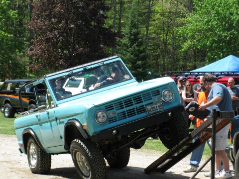 1973 Ford Bronco - A light blue 1973 Ford Bronco is positioned on a ramp, with onlookers gathered around.