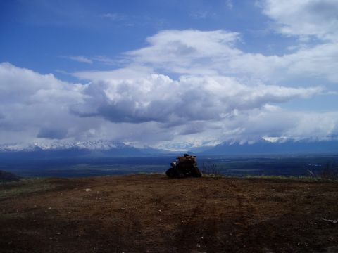 2000 Ford E350 - An ATV sits on a hilltop with a vast landscape and cloudy sky behind it.