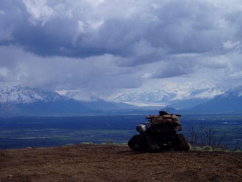 2000 Ford E350 - An all-terrain vehicle is parked on a dirt overlook, with a vast landscape of mountains and a cloudy sky behind it.