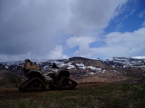 2000 Ford E350 - ATV equipped with tracks for snow travel sits on a hill overlooking a mountain range.