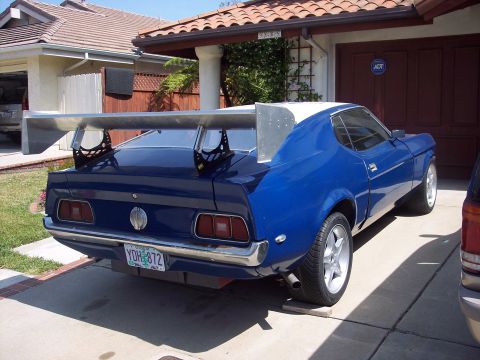 1971 Ford Mustang - Rear view of a blue 1971 Ford Mustang with a custom spoiler and white roof parked in a driveway.