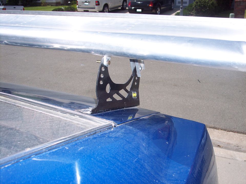 Black adjustable wing stand mounting an aluminum rear wing to a blue car's decklid
