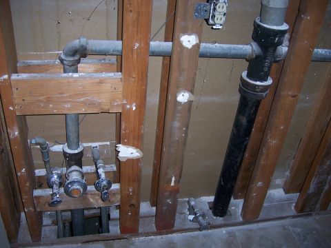 1991 Ford Bronco - A view of plumbing pipes and wooden studs within a wall, likely during renovation or construction.