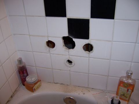 1991 Ford Bronco - Holes are visible in the tiled wall above a bathtub, suggesting plumbing issues.
