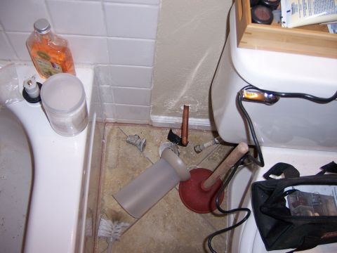 1991 Ford Bronco - A bathroom scene shows a toilet and bathtub with various plumbing tools and supplies scattered around the floor.