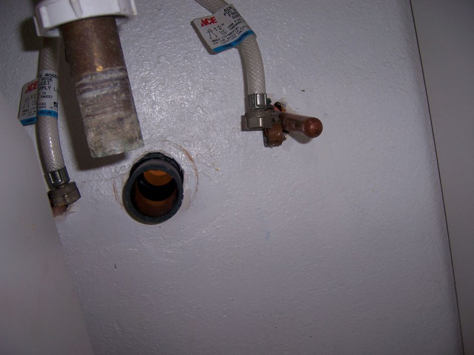 Plumbing pipes and valves under a sink with ACE brand supply lines