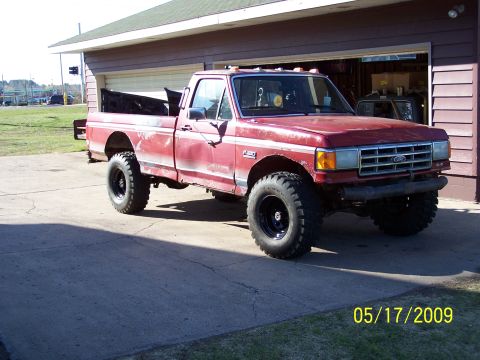 1989 Ford F-150 - Red 1989 Ford F-150 pickup truck with aftermarket wheels and tires sits outside a garage.
