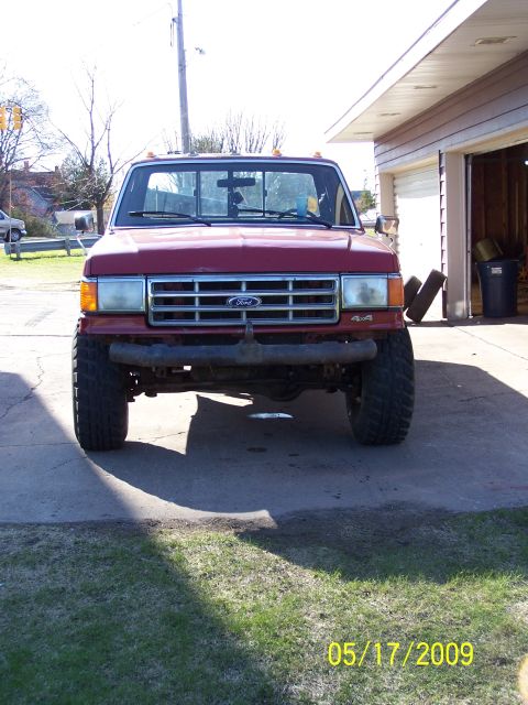 1989 Ford F-150 - This red Ford pickup truck, likely from the late 1980s, is shown from the front in a driveway setting.