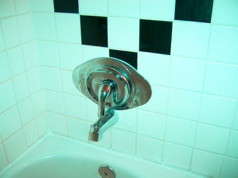 1991 Ford Bronco - A chrome bathtub faucet is shown against a backdrop of white tiles with a black checkerboard pattern.
