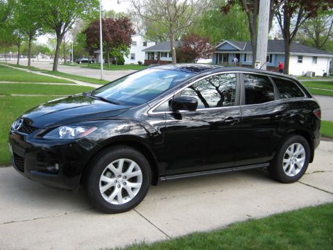 2007 Mazda CX-7 - A black Mazda CX-7 is parked on a concrete driveway in front of a residential house.