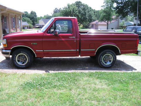 1996 Ford F-150 - A red 1996 Ford F-150 pickup truck is seen from the side, parked in a residential area.