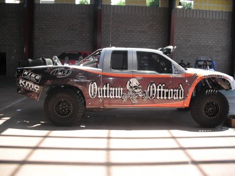 1986 Ford Bronco - A custom off-road truck with extensive modifications and graphics is parked indoors.