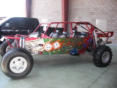 1986 Ford Bronco - This custom dune buggy features a unique casino-themed paint job with dice and dollar bill graphics, seen alongside a black pickup truck.