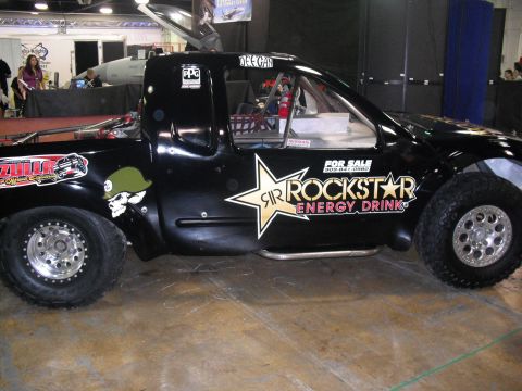 1986 Ford Bronco - Custom black truck with racing decals and a 'For Sale' sign is displayed indoors.