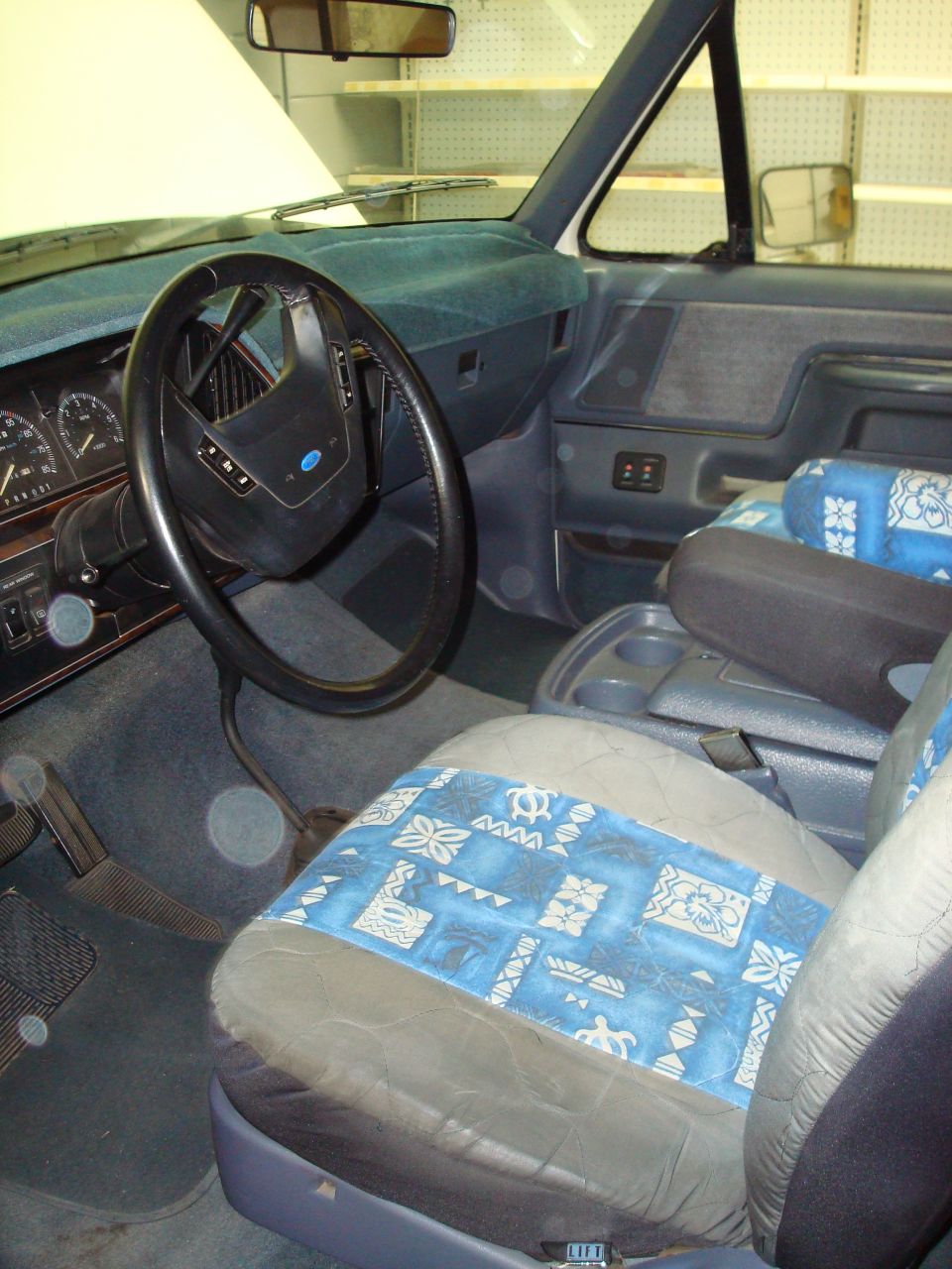 1990 Ford Bronco interior with blue patterned seat covers and a dark dashboard