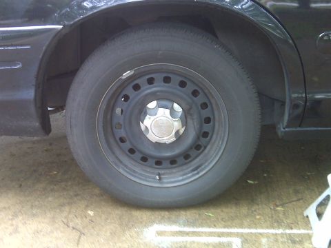2001 Ford Crown Victoria - A close-up view of a vehicle's steel wheel and the surrounding bodywork.
