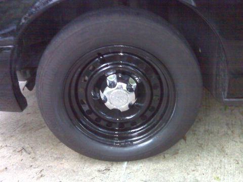 2001 Ford Crown Victoria - Close-up of a black steel wheel with a chrome hubcap on a black vehicle.