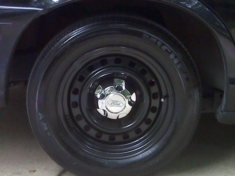 Black steel wheel with a chrome Ford hubcap on a 2001 Ford Crown Victoria
