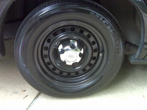 2001 Ford Crown Victoria - Close-up of a black steel wheel with a chrome Ford center cap and a Michelin tire.