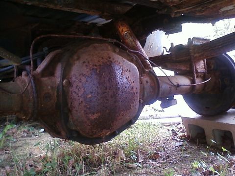 1990 Ford Bronco - The underside of a vehicle shows significant rust on its rear axle and suspension components.