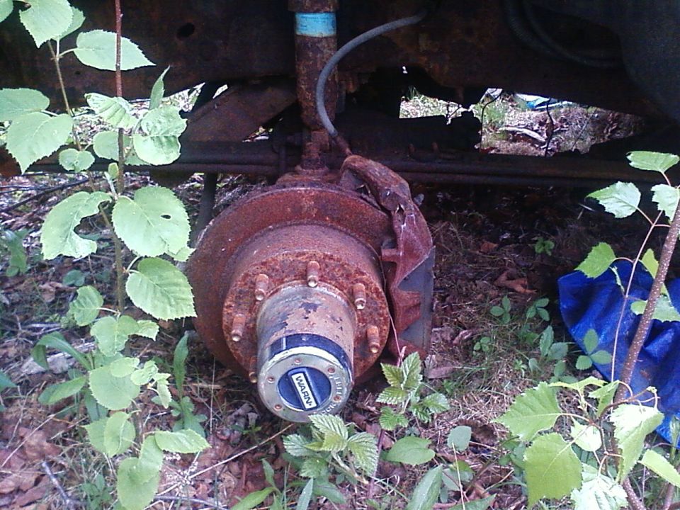 Close-up of a rusty wheel hub with a blue WARN decal, part of a vehicle's suspension system