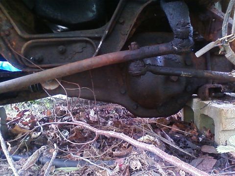 1990 Ford Bronco - The underside of a vehicle shows significant rust and wear on its mechanical parts.