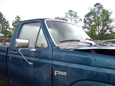 1985 Ford F-250 - A blue pickup truck is seen from the side, with the F250 badge clearly visible on the fender.