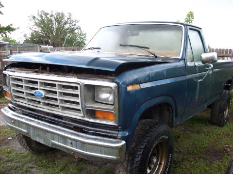 1985 Ford F-250 - This blue Ford pickup truck appears to be from the early 1980s, with its hood up and showing signs of wear.