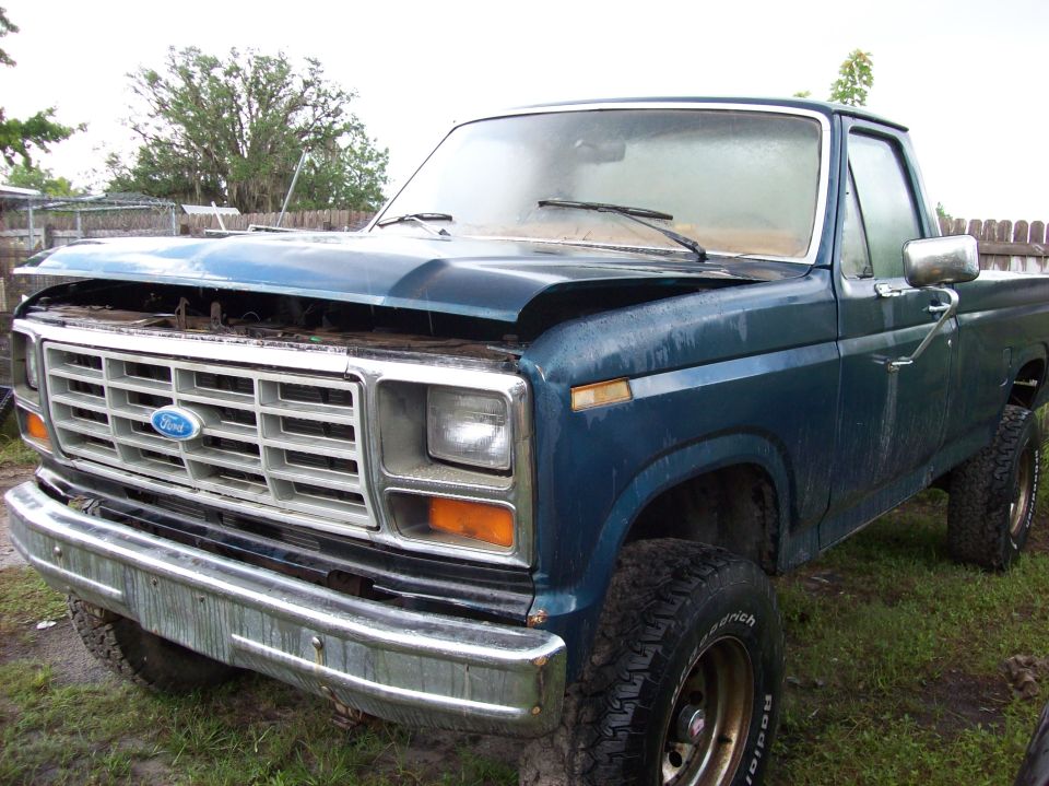 Blue Ford pickup truck with hood open, parked outside
