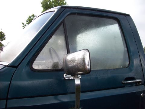 1985 Ford F-250 - Side view of a dark green pickup truck cab, showing the door and window details.