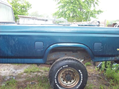 1985 Ford F-250 - A blue pickup truck is seen from the side, with a close-up of its rear wheel and tire.