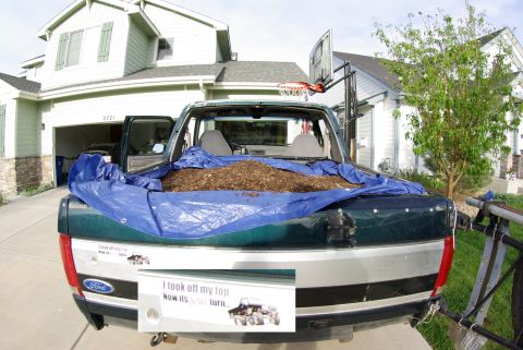 1995 Ford Bronco - A Ford pickup truck is parked in a driveway, its bed filled with mulch and covered by a blue tarp.