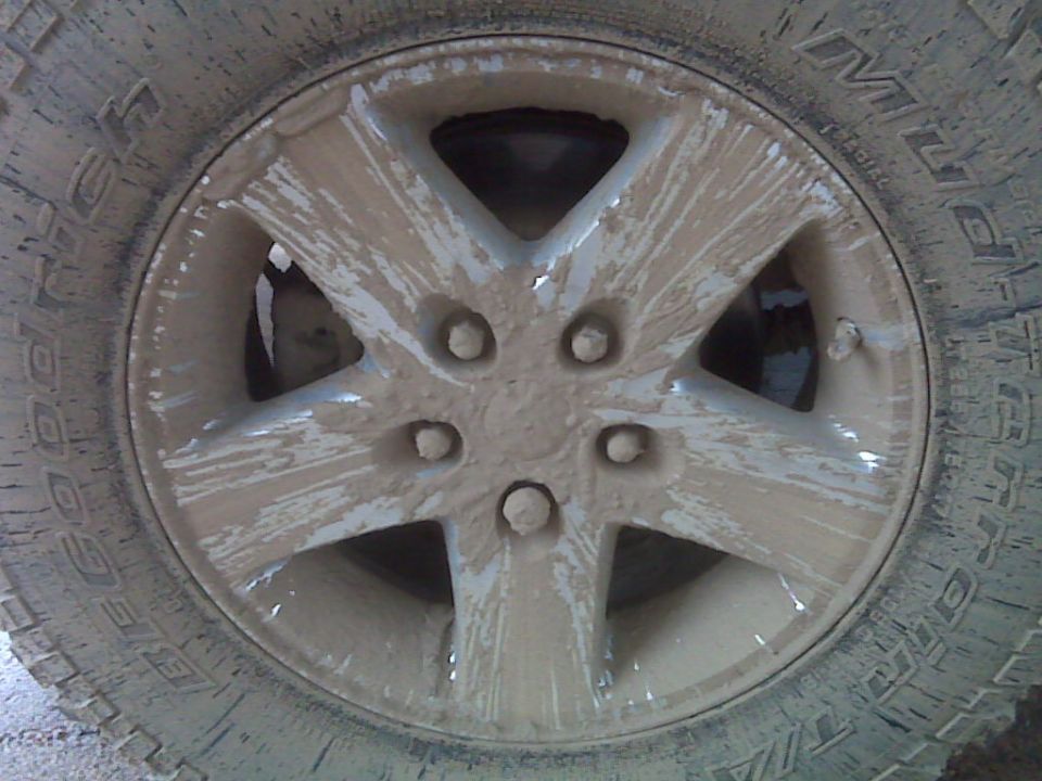 Mud-splattered Jeep Wrangler wheel with five spokes and a BFGoodrich tire
