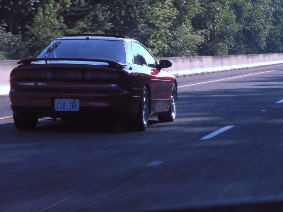 Red Ford Probe driving on highway, rear view