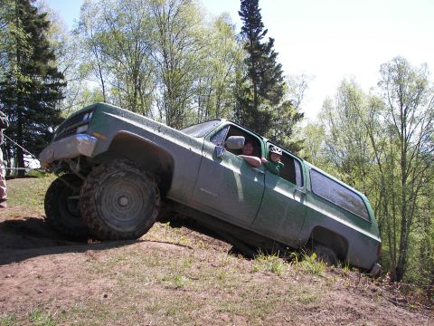 1990 Chevrolet Suburban - This 1990 Chevrolet Suburban is navigating a steep, muddy incline with two occupants visible.