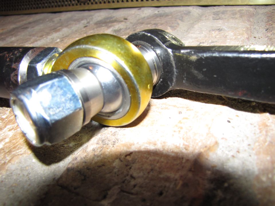 Close-up of a tie rod end with a gold-colored bushing and a hex nut