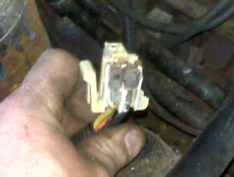 1995 Ford Bronco - A hand holds a damaged electrical connector with visible wires, suggesting a repair or diagnostic situation.