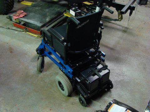 1948 Jeep Wrangler - A power wheelchair with a blue frame and black seat is shown in a workshop setting.