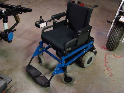 1948 Jeep Wrangler - An electric wheelchair is shown in a workshop setting with other mechanical parts visible.