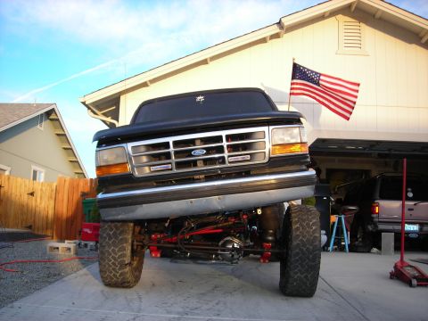 1994 Ford Bronco - This lifted Ford F-150 truck displays its suspension modifications, with an American flag flying in the background.