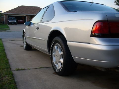 1995 Ford Thunderbird - A silver 1995 Ford Thunderbird is parked in a driveway with a garage in the background.