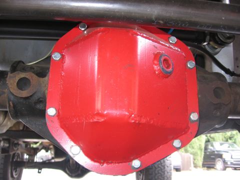 1989 Ford Bronco - A red differential cover is installed on a vehicle's axle, with another vehicle in the background.