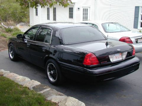 2003 Ford Crown Victoria - Rear view of a black 2003 Ford Crown Victoria with aftermarket wheels.