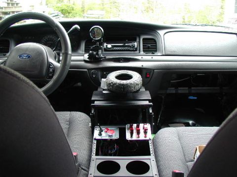 2003 Ford Crown Victoria - The interior of a 2003 Ford Crown Victoria shows a custom console with switches and a gauge, along with a spare tire on top.